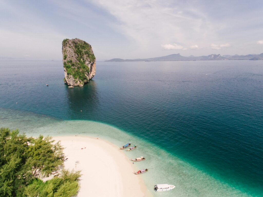 A breathtaking aerial view of a tropical beach with a unique sea stack and clear blue waters.